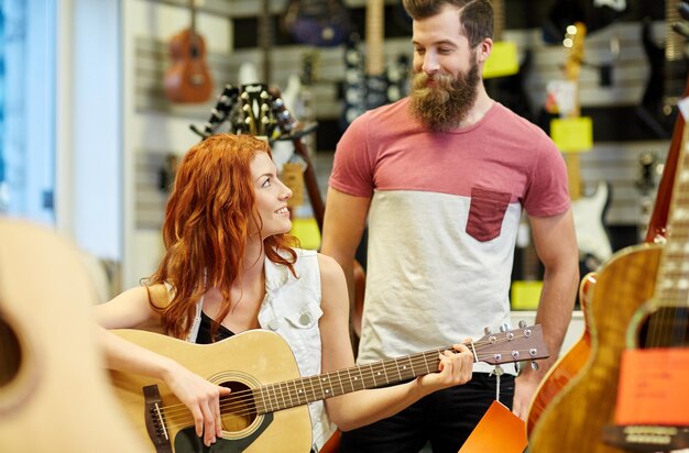 music sale people musical instruments entertainment concept happy couple musicians with guitar music store